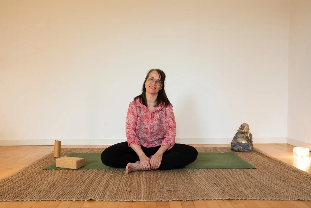 Photo von Sabine Schmitt im Yoga Schneidersitz auf dem Boden sitzend.